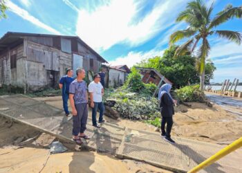 KETUA Kampung Batak Rabit, Shuhaila Ahmad Jamlos (depan) bersama penduduk meninjau keadaan rumah di tebing Sungai Perak yang terjejas akibat hakisan di Teluk Intan, semalam. – UTUSAN/AIN SAFRE BIDIN