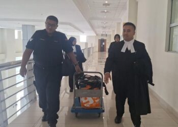 MUHAMMAD NOR (kanan) dan anggota polis yang membawa eksibit kes dari mahkamah itu, hari ini. -FOTO/ ISKANDAR SHAH MOHAMED