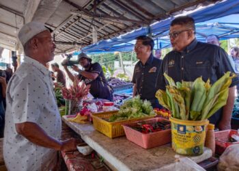 AB. Rauf Yusoh (kanan) menyantuni seorang peniaga pada Majlis Penyempurnaan Cadangan Pembinaan Pasar Baharu Batang Tiga di Klebang, Melaka. - UTUSAN/MUHAMMAD SHAHIZAM TAZALI