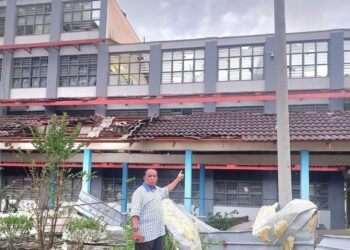 ABDUL Razak Khasbullah menunjukkan bumbung salah sebuah bangunan di SK Sijangkang Jaya yang tercabut akibat ribut dan angin puting beliung di Kuala Langat, Selangor, hari ini. - UTUSAN / ABDUL RAZAK IDRIS