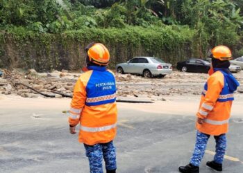 DUA anggota APM memantau keadaan tanah runtuh yang berlaku berhampiran sebuah pasar raya di Paya Terubong, Ayer Itam, George Town, Pulau Pinang hari ini.-GAMBAR/APM PULAU PINANG