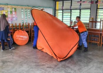 ANGGOTA Angkatan Pertahanan Awam Malaysia (APM) Pulau Pinang melipat khemah yang diguna untuk menempatkan mangsa banjir di SK Tan Sri Awang Had Salleh, Balik Pulau, Pulau Pinang selepas PPS itu ditutup sepenuhnya kira-kira pukul 12.45 tengah hari tadi.-GAMBAR/PKOB BARAT DAYA