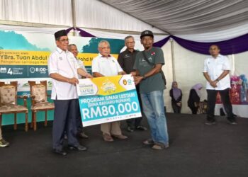 ABDUL Khudis Mohd. Naaim (kiri) menyampaikan replika cek kepada penerima Program Sinar Lestari YAPEIM (bina baharu rumah) sewaktu Majlis Perasmian Projek Pembangunan Komuniti YAPEIM (PPKY) Kolaborasi Yayasan Diraja Sultan Mizan (YDSM) di Perkampungan Konservasi Gajah Kenyir, Hulu Terengganu, hari ini. -  UTUSAN/ NOOR HAYATI MAMAT