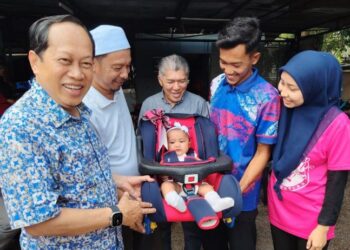 AHMAD Maslan (kiri) menyampaikan kerusi bayi kepada Syaidah Nor Amanda Mohd. Amirul Fikri berusia lima bulan di Kampung Parit Seraya, Benut, Pontian, hari ini. - UTUSAN/MUHAMMAD ZIKRI