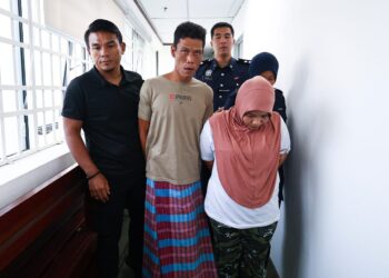 NURHAYATI (kanan) dan suami, Siswadi diringi polis bagi menghadapi pertuduhan di Mahkamah Sesyen Ipoh kerana menganiaya anak lelaki mereka sehingga maut, bulan lalu. - UTUSAN