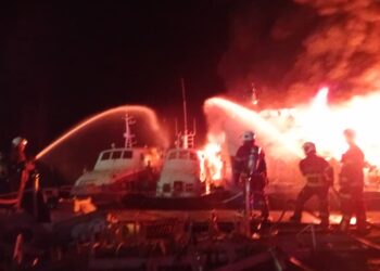 ANGGOTA bomba memadam kebakaran tiga buah feri penumpang yang terbakar di sebuah dermaga di Langkawi. - IHSAN BOMBA