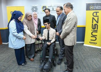 MOHD. Hafiz Yusoff (dua dari kanan) melihat kerusi roda elektrik yang disumbangkan kepada Muhammad Nor Syahidan Abdul Manaf pada majlis penyerahan kerosi roda di UniSZA, Gong Badak, Kuala Nerus, Terengganu.