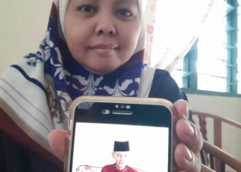 SUSILAWATI menunjukkan gambar arwah bapanya yang maut dalam nahas meragut dua nyawa di Kilometer 18 Jalan Mawai-Kuala Sedili petang semalam.