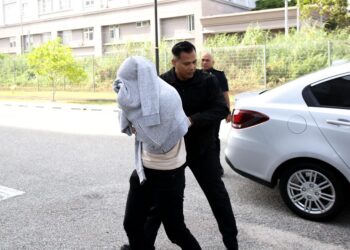 TERTUDUH semasa dibawa oleh polis untuk menghadiri prosiding perbicaraan di Mahkamah Sesyen Kota Bharu, Kelantan. - UTUSAN/KAMARUL BISMI KAMARUZAMAN