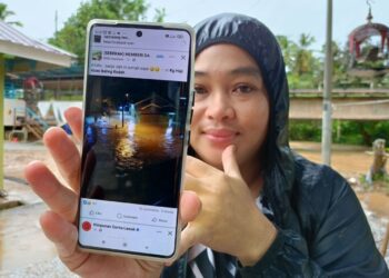 NOR Amirah Abdul Muin menunjukkan tangkap layar Facebook memaparkan gambar rumahnya yang digenangi air di Kampung Haji Abas, Baling.