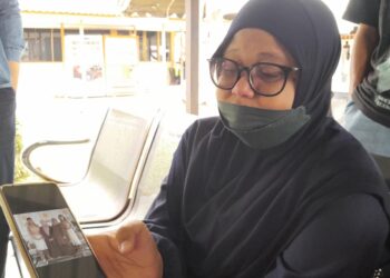 Maryani menunjukkan gambar Fazrizal Izuan anak bongsunya yang terlibat dalam nahas di KM 56 Lebuhraya Senai - Desaru semalam