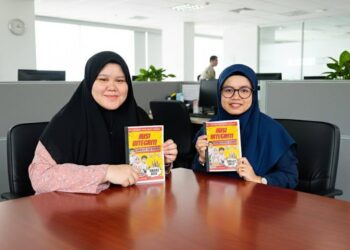 HASLINDA Jama'in (kanan) dan Nur Maisarah Syahirah Zainal Abidin (kiri) menunjukkan karya kerjasama mereka bersama SPRM iaitu Komik 'Misi Integriti: Perang Rasuah Bermula'