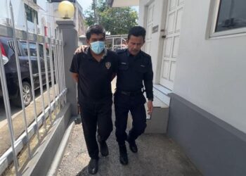 ANGGOTA polis (kanan) mengiringi Mohd. Afizzafri Mohammed Residalan (kiri) keluar dari Mahkamah Sesyen Kemaman, Terengganu. -UTUSAN/NIK NUR IZZATUL HAZWANI NIK ADNAN