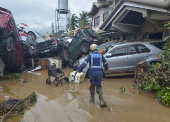 SEORANG anggota penyelamat berjalan menghampiri deretan kereta yang dihanyutkan banjir akibat Taufan Kalmaegi di kawasan perumahan di Cebu City, tengah Filipina.-AFP