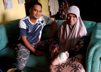 MOHAMMAD Rozaimi Ismail (kiri) bersama ibunya,  Aminah Abdullah menunjukkan tapak kaki kirinya yang dibedah di Felda Kota Gelanggi Empat di Jerantut, Pahang.