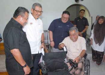 WAN Ahmad Dahlan Abdul Aziz menyampaikan sumbangan kerusi roda elektrik kepada Azhar Hashim Kampung Pulau Melaka, Peringgit, Melaka hari ini.-UTUSAN/AMRAN MULUP