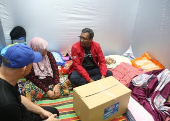 ZURAIDI Rahim (duduk, kanan) melawat mangsa banjir warga emas yang terlantar sakit ketika mengunjungi PPS Sekolah Kebangsaan Seri Perdana di Alor Setar.