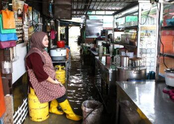 Peniaga, Nabila Ismail, 31 terpaksa berniaga di dalam air yang bergenang di warung miliknya ekoran kejadian banjir di Kampung Seberang Anak Bukit, Alor Setar hari ini. UTUSAN/ SHAHIR NOORDIN