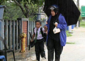 SEORANG wanita membawa pulang anaknya selepas SK Dato Wan Kemara dinaiki air di Changlun, Kubang Pasu.