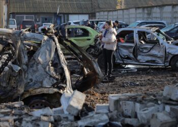 ORANG awam memeriksa kereta yang musnah di kawasan parkir sebuah stesen servis kereta, susulan serangan udara Russia di Odesa.- AFP