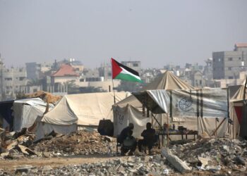 RAKYAT Palestin duduk di luar kediaman sementara di sepanjang jalan berhampiran kem pelarian Nuseirat di tengah Gaza.- AFP