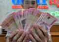 SEORANG pekerja menunjukkan wang kertas Rupiah Indonesia di sebuah premis pengurup wang di Jakarta. – AFP