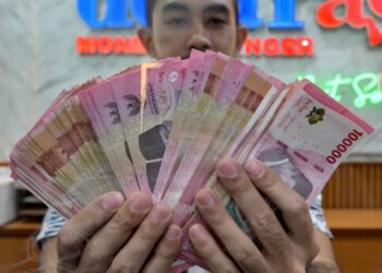 SEORANG pekerja menunjukkan wang kertas Rupiah Indonesia di sebuah premis pengurup wang di Jakarta. – AFP