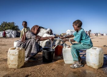 PELARIAN Sudan mengisi air di dalam bekas di kem transit di Tine, Chad. – AFP