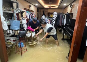 NABIL Afif Zulkefli, 37, (kanan) mengemas rumah yang dinaiki air di Taman Desa Jarak, Bintong, Perlis, Kangar, Perlis hari ini.- UTUSAN/ASYRAF MUHAMMAD