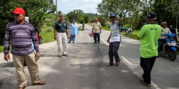penduduk menunjukkan keadaan jalan rosak yang akibat kerja-kerja penanaman paip  di Jalan Darat, Changlun. – UTUSAN/ SHAHIR NOORDIN