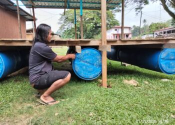 NORHISAM Nahari memasang tong pelampung di bawah lantai kedai makan sebagai persediaan musim banjir di Kampung Bantal, Ulu Tembeling di Jerantut, Pahang.