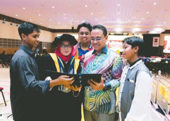 FADILAH Hanim Abdullah berkongsi kegembiraan dengan anak dan suaminya selepas berjaya menggenggam Ijazah Doktor Falsafah (PhD) pada Istiadat Konvokesyen Ke-15 UMK di Bachok, Kelantan. – UTUSAN/KAMARUL BISMI KAMARUZAMAN