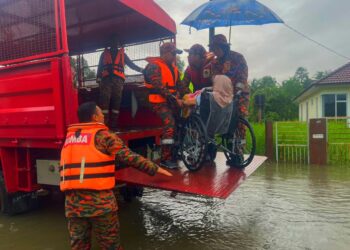 ANGGOTA Bomba dan Penyelamat memindahkan mangsa banjir di Kampung Mujur, Bachok, Kelantan.-IHSAN JBPM KELANTAN.