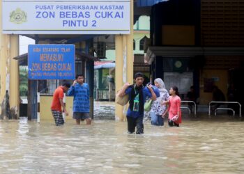 SEBAHAGIAN penduduk terpaksa meredah banjir susulan limpahan air Sungai Golok di Pusat Pemeriksaan Kastam Zon Bebas Cukai Pintu 2, Rantau Panjang, Kelantan hari ini.-UTUSAN/KAMARUL BISMI KAMARUZAMAN.