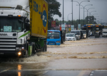 KENDERAAN berat dan pacuan empat roda mengharungi air yang melimpah ke jalan utama di Pekan Changlun, Kubang Pasu. - UTUSAN/ SHAHIR NOORDIN