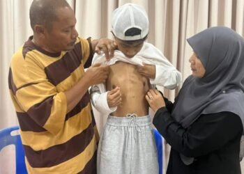 SALEHUDIN Mat Rasad (kiri) dan Nor Ezah Abdul Rahman menunjukkan kesan pembedahan jantung berlubang Mohammad Azim ketika berusia lapan tahun di Jerantut, Pahang.