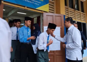 AHMAD Zamri Md Isa (kanan) bersalaman dengan calon Sijil Pelajaran Malaysia (SPM) di Sekolah Menengah Kebangsaan (SMK) Seri Pekan di Pekan, Pahang. - UTUSAN/SHAIKH AHMAD RAZIF