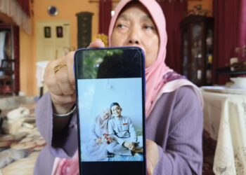 ZAITON Abdul Rahman menunjukkan gambar Mohd. Fuad Fahmie yang mati ditembak di Sungai Golok, Thailand malam tadi-UTUSAN/YATIMIN ABDULLAH