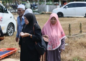 WAN Fatihah Mat Hussien (kiri) kelihatan sugul semasa menghadiri upacara pengebumian arwah suaminya di Tanah Perkuburan Islam Kampung Apam, Pasir Mas, Kelantan semalam-UTUSAN/KAMARUL BISMI KAMARUZAMAN.