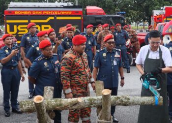 MOHAMAD Shoki (depan, dua dari kanan) melihat H'Ng Mooi Lye (kanan) melakukan gimik memotong pokok pada Majlis Penyerahan Bot Bomba Komuniti dan Pemeriksaan Aset Kebombaan sempena musim Monsun Timur Laut di Batu Kawan, Pulau Pinang hari ini.-UTUSAN/DANIAL SAAD