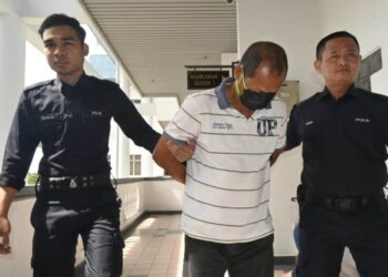TERTUDUH yang diiringi anggota polis mengaku tidak bersalah atas pertuduhan melakukan amang seksual fizikal di Mahkamah Sesyen, Ayer Keroh, Melaka hari ini. - UTUSAN/AMRAN ALI