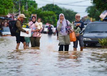 PENDUDUK dilihat keluar dari kawasan yang terjejas banjir ketika tinjauan Utusan Malaysia di Kampung Padang Jawa di sini, hari ini. - UTUSAN/ISKANDAR ISHAK