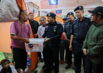 MOHD. Yusoff Mamat (tiga kanan) menyerahkan bantuan kepada salah seorang mangsa banjir yang berlindung di PPS SK Kok Keli, Tumpat, Kelantan hari ini-UTUSAN/KAMARUL BISMI KAMARUZAMAN.