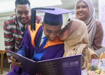 MOHD. Khairul Ab. Aziz (dua dari kiri) menerima kucupan daripada ibunya, Sarinah Abdullah, 65, sambil diperhatikan oleh dua adiknya iaitu Farah Waheeda, 32, (kanan) dan Mohd. Khairi, 38, selepas Upacara Konvokesyen Ke-63 USM di George Town, Pulau Pinang, petang semalam.-UTUSAN/DANIAL SAAD