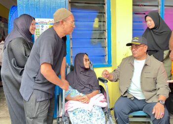 MUHAMMAD Sanusi Md. Nor (duduk, kanan) menyantuni mangsa banjir yang berlindung di PPS SK Seri Perdana, Alor Setar.