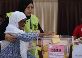 PETUGAS SPR membantu warga emas mengundi di Sekolah Kebangsaan Serusup, Tuaran, Sabah.-UTUSAN/AMIR KHALID