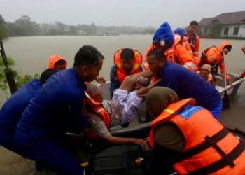 ANGGOTA Angkatan Pertahanan Awam Malaysia (APM) membantu mengangkat mangsa yang terjejas akibat banjir di Kampung Surau Haji Yaakob, Bukit Payung, Marang, Terengganu. -UTUSAN/PUQTRA HAIRRY