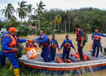 MOHD. Bukhori Mat Sidik (kiri) membantu anggota APM Kubang Pasu memindahkan penduduk yang masih terperangkap dalam bencana banjir di Kampung Paya Tok Kiong, Jitra di Kubang Pasu. - UTUSAN/ SHAHIR NOORDIN
