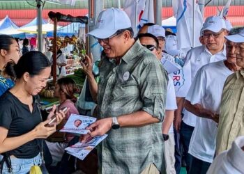 JONISTON Bangkuai (kiri) dan dan Louis Rampas mengedarkan risalah kempen kepada penduduk Tomis, Kiulu.