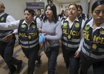 Betssy Chavez (baju kelabu) diiringi anggota polis. - AGENSI